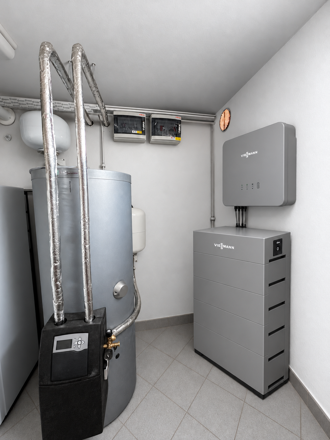 locale tecnico con bollitore e tubazioni coibentate, quadri elettrici, inverter a parete e batteria di accumulo a torre